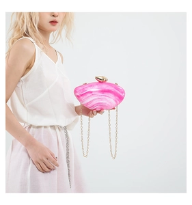 Detail of pink marble acrylic shell evening bag with golden chain and sphere clasp
