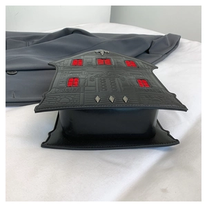 Macro shot of gothic house-shaped purse with red window details and metal studs