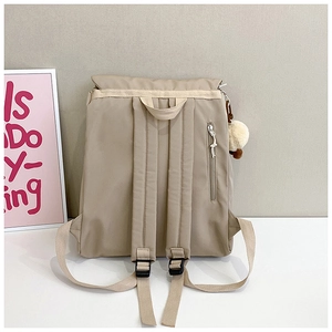 Detail of beige nylon backpack with anti-theft back pocket and plush ball accessory