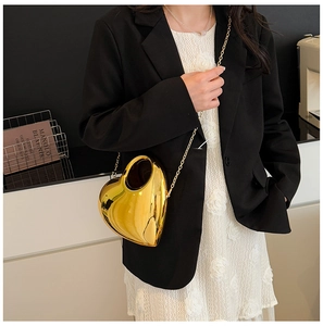 Detailed view of glossy gold heart-shaped acrylic bag with elegant metal chain strap