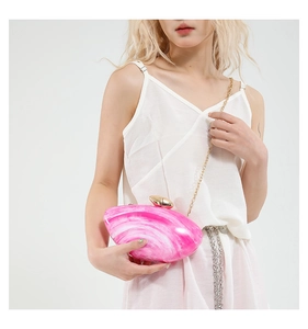 Pink marble acrylic clutch bag with gold shell clasp shown on model's shoulder
