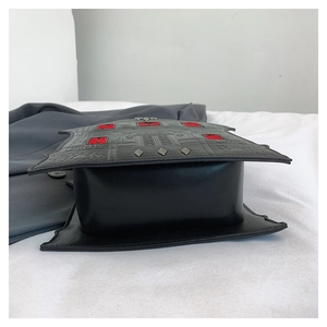 Detailed side view of house-shaped black PU bag with silver studs and red windows