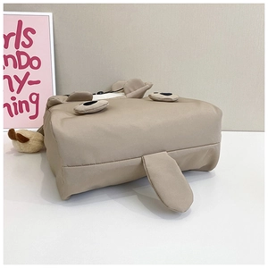 Detailed bottom view of khaki cartoon dog backpack showing soft fabric and plush ball charm