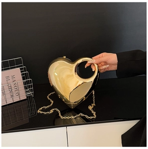 Detail of a gold heart-shaped acrylic bag with mirror finish and round hollow handle