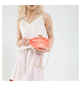 Macro shot of pink marble acrylic evening clutch with gold metal clasp and chain