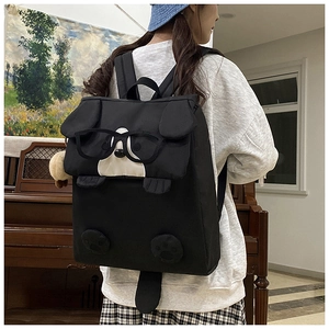 Detail of cute black cartoon dog backpack with 3D ears and glasses on female model