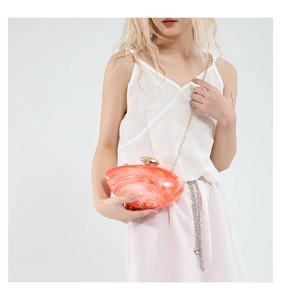 Close-up of pink marble acrylic clutch bag with gold oval clasp and metal chain strap