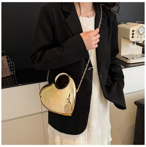 Detail of heart-shaped gold acrylic clutch with metallic chain and circular handle