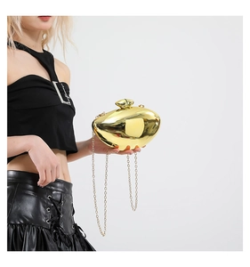 Detail of a shiny gold asymmetric acrylic clutch bag with a metal chain for evening wear