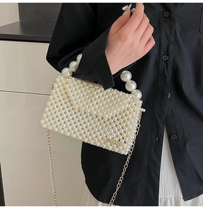 Detail of handmade ivory pearl beaded handbag with golden metal chain strap and top handle