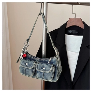 Detail of vintage blue denim underarm bag with silver flower charms and front pockets