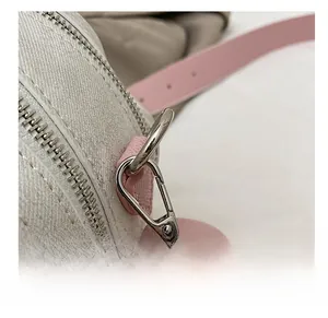 Macro shot of silver metal hook and pink leather strap on textured canvas bag