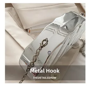 Detail of silver metallic shell bag showing hardware hook and wavy textured surface