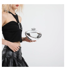 Close-up of a silver mirror finish metallic oval clutch bag with a spherical top clasp