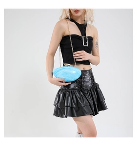 Detail of light blue acrylic clutch with marble texture and elegant gold chain strap