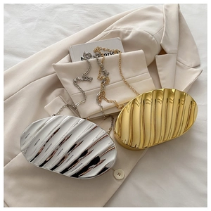 Detail view of gold and silver metallic shell clutch bags with 3D wavy texture on a blazer