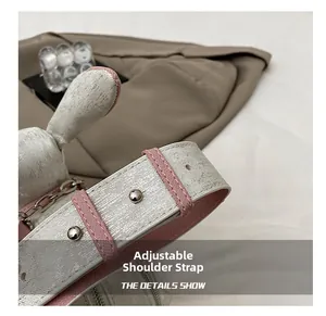 Close-up of adjustable white metallic shoulder strap with pink stitching and chain detail