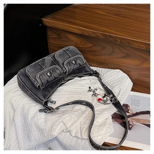 Detail of black washed denim underarm bag with vintage metal buckles and beaded charm