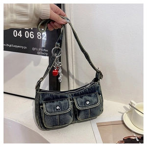 Detailed close-up of vintage denim shoulder bag featuring twin metal-buckle front pockets