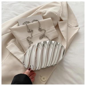 Macro view of silver metallic shell clutch featuring vertical wave pleats and chain