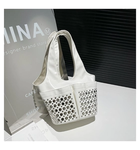 Macro detail of white patent leather tote bag featuring stylish silver rivets and pockets