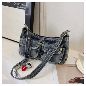 Close-up of a blue denim shoulder bag featuring two front flap pockets and heart charms