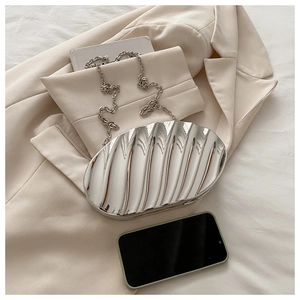 Macro shot of silver metallic shell-shaped clutch with wave texture and chain strap