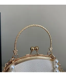 Detail of white shell bag with pearl chain and vintage engraved golden metal handle