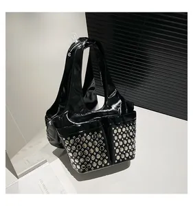 Close-up of black patent leather underarm bag featuring metallic silver rivet details