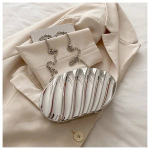 Detailed view of silver metallic shell bag with textured wave pattern and chain strap