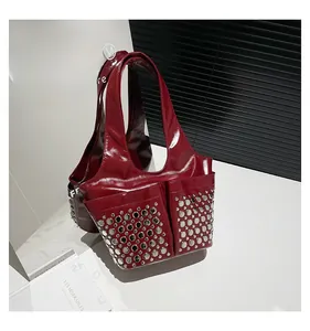 Detail of dark red patent leather tote bag with silver metal studs on front pockets
