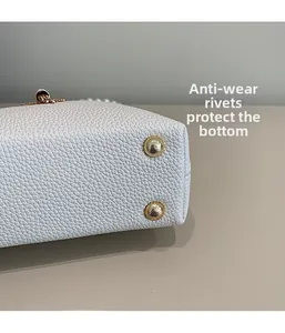 Macro shot of gold anti-wear rivets on white litchi grain leather bag base