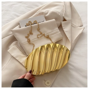 Detail of gold seashell clutch bag featuring pleated metallic texture and thin chain strap