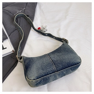 Close-up of retro washed denim shoulder bag with adjustable strap and rabbit charm