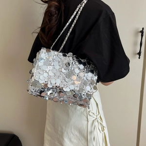 Chic sac bandoulière argenté à paillettes avec chaîne porté par un mannequin en fête