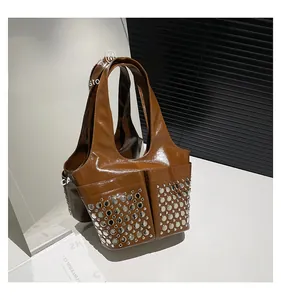 Detail of caramel leather tote bag showing silver rivets and glossy polished finish