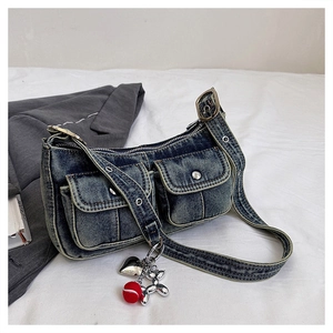 Detailed view of washed denim shoulder bag featuring utility pockets and creative pendants