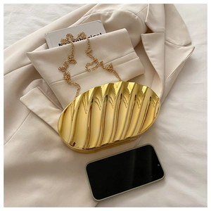 Close-up of golden shell bag with luxury wavy texture and fine metallic chain strap