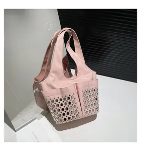Detail of pink patent leather shoulder bag with metallic stud rivets and dual front pockets