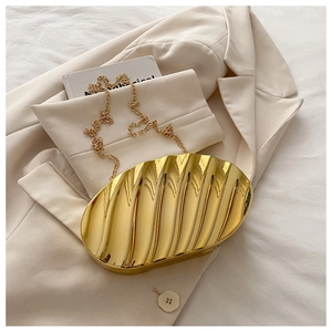 Detail of gold shell-shaped clutch bag showing metallic wave texture and chain strap