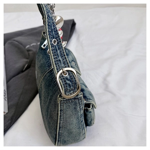 Detail of vintage washed blue denim bag with silver chain strap and heart pendant charm