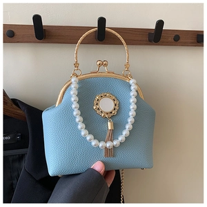 Detail of light blue lychee leather shell bag with pearl chain and golden tassel
