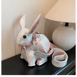 Detail of cute rabbit crossbody bag with cracked white leather and pink strap