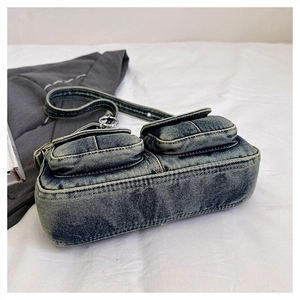 Detail of vintage washed denim bag with side flap pockets and silver metal buckles