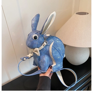 Detail of cute blue rabbit shoulder bag with metallic texture and bow tie decoration