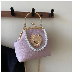 Detail of lilac shell bag with gold heart ornament and white pearl handle strap
