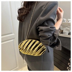 Detail of gold pleated metal evening clutch bag with slim chain strap on a model