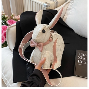 Detail of cute rabbit crossbody bag with pearlized finish and pink bow accent