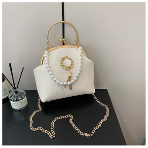 Detail of white lychee leather shell bag with pearl handle and golden tassel ornament