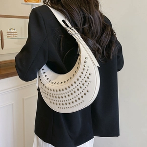 Sac croissant ivoire chic avec clous argentés et bandoulière ajustable sur modèle